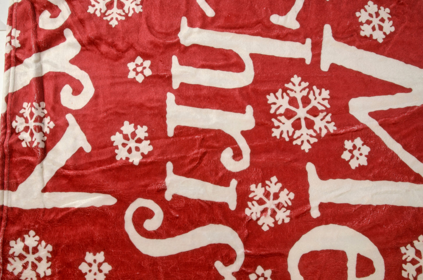 A red and white Christmas-themed blanket with text and snowflake patterns.