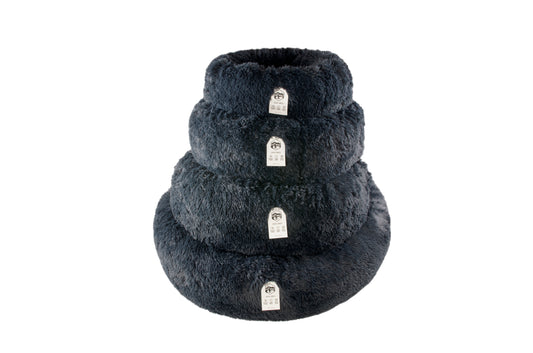 A round donut-shaped pet bed made of navy material, with the brand tag The Fat Mile showing on a tag.