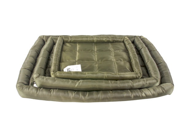A waterproof dog crate bed in green color, displayed in a stack of different sizes. The Fat Mile tag attached.